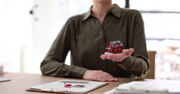 Agent nieruchomości trzyma zabawkowy domek w ręku zbliżenie 4k film slow motion. Koncepcja zakupu apartamentów - Materiał filmowy, wideo