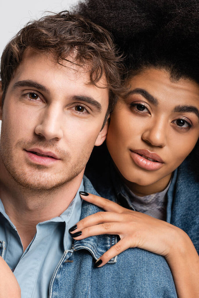 portrait of curly african american woman and good looking man looking at camera isolated on grey  - Photo, image