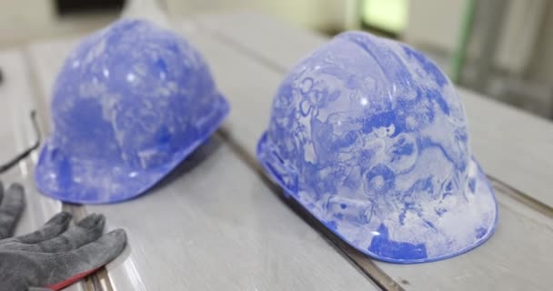 Dirty protective construction helmets lying on floor laminate closeup 4k movie slow motion. Construction work safety equipment concept - Footage, Video