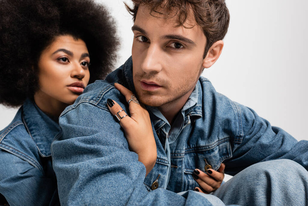 african american woman hugging stylish man in denim clothes isolated on grey  - Foto, immagini