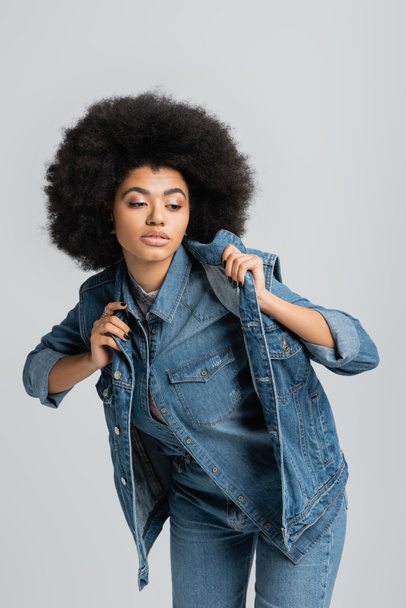giovane donna afroamericana in giacca di denim distogliendo lo sguardo isolato sul grigio  - Foto, immagini
