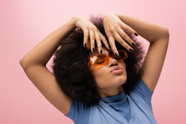 Retrato de mujer afroamericana en gafas de sol haciendo pucheros labios aislados en rosa  - Foto, imagen