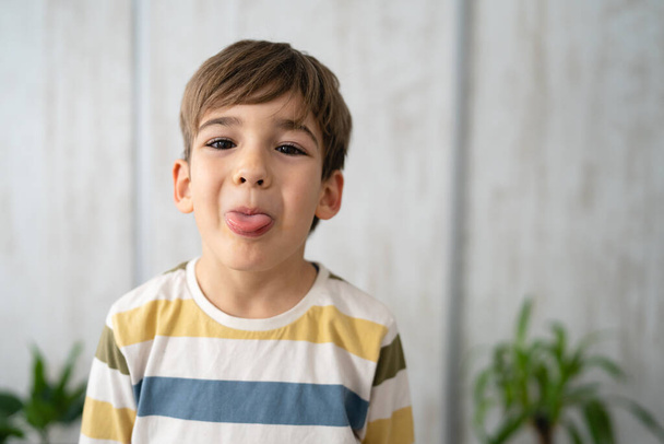 muotokuva valkoihoinen poika kuusivuotias ulkoneva kieli kotona - Valokuva, kuva