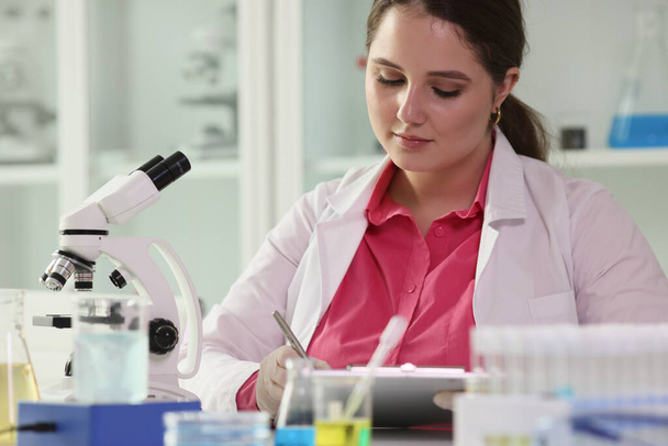 Female scientist taking notes while reviewing results of scientific experiments in laboratory. Education, chemical and science research concept. - Photo, Image