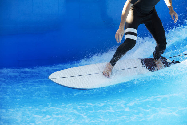 Een surfer in een wetsuit op de golven in een zwembad - Foto, afbeelding