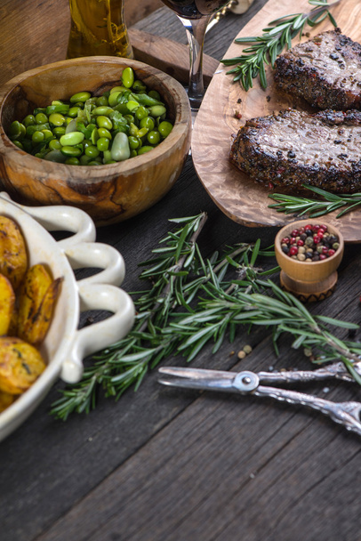 Bistecca di manzo medio rara alla griglia con erbe aromatiche sul tavolo rustico
 - Foto, immagini