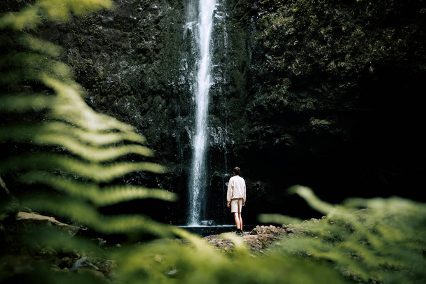 Levada do Caldeiro Verde, Madeira, zastřelen dronem člověka stojícího pod majestátním vodopádem uprostřed nedotčené přírody - Fotografie, Obrázek
