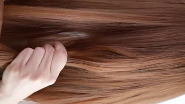 Closeup on a young woman combing her hair - Video