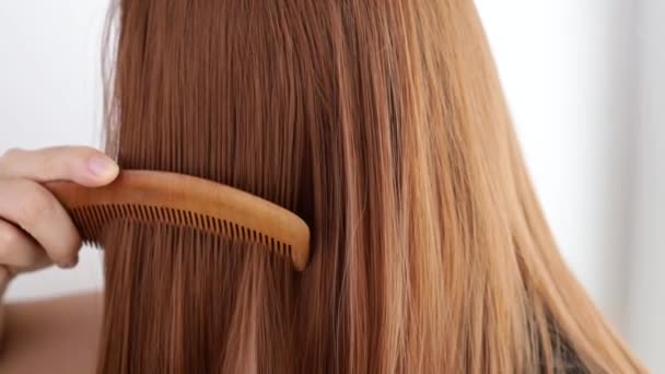 Closeup on a young woman combing her hair - Video, Çekim