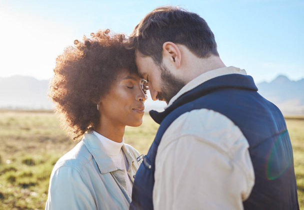 Intimacy, love and couple in nature on a farm for a romantic anniversary or valentines day date. Intimate, affection and interracial man and woman in a romance moment together on a eco friendly field. - 写真・画像
