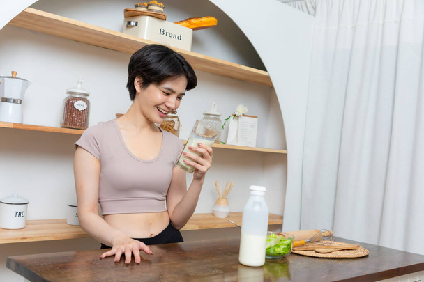 Azjatka młoda piękna kobieta pije szklankę mleka w kuchni w domu. koncepcja opieki zdrowotnej - Zdjęcie, obraz