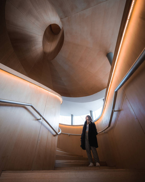 girl standing on wooden spiral staircase - Valokuva, kuva