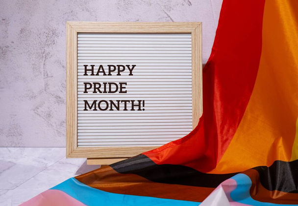HAPPY PRIDE MONTH inscription positive quote phrase text frame on Rainbow LGBTQIA flag made from silk material. Symbol of LGBTQ pride month. Equal rights. Peace and freedom. Support LGBTQIA community. Diversity equality - Foto, Imagen
