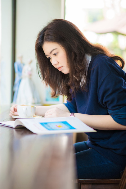 ázsiai diák nő forró kávét és a caf magazin pihentető - Fotó, kép