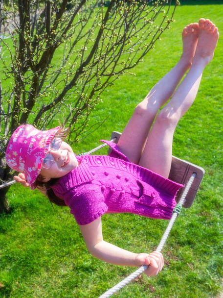 Happy girl in a pink hat having fun on a swing outdoor  - Photo, Image