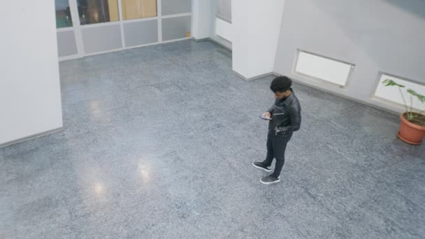 People walking at college lobby. African American man stands and texts by phone. Multi ethnic friends meet. Tracking and monitoring system. Observation and CCTV technologies. Security camera shooting. - Séquence, vidéo