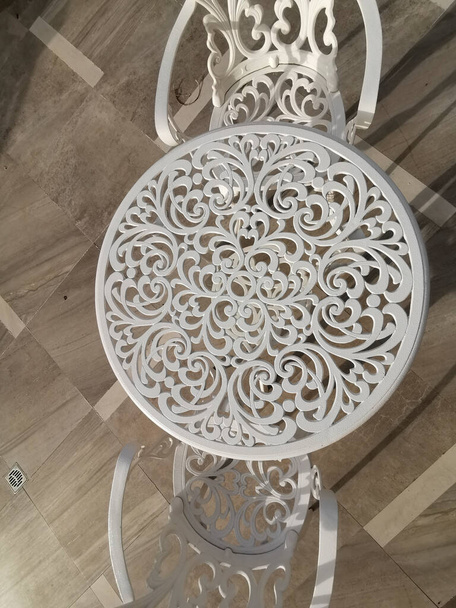 white wrought iron table and chair with floral motifs on terrace at dawn. High quality photo - Zdjęcie, obraz