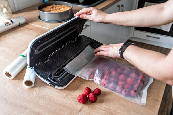 Woman use vacuum sealer packing machine for long-term storage of products. Vacuum strawberries packaging for long-term storage. - Fotografie, Obrázek