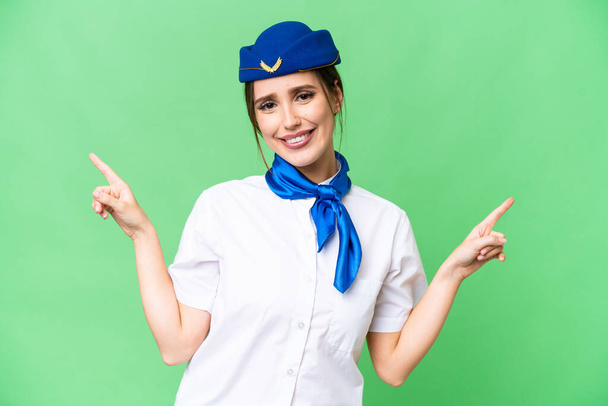Airplane stewardess over isolated chroma key background pointing finger to the laterals and happy - Fotografie, Obrázek