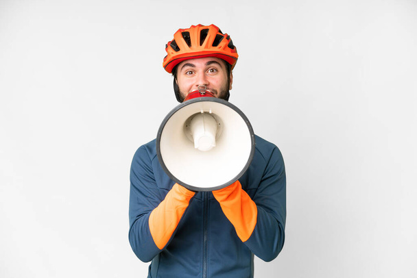 Young cyclist man over isolated white background shouting through a megaphone - Foto, Bild