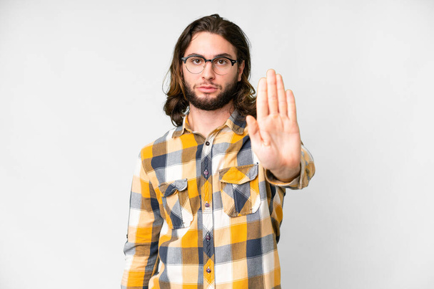 Молодой красивый мужчина на изолированном белом фоне делает остановку жест - Фото, изображение