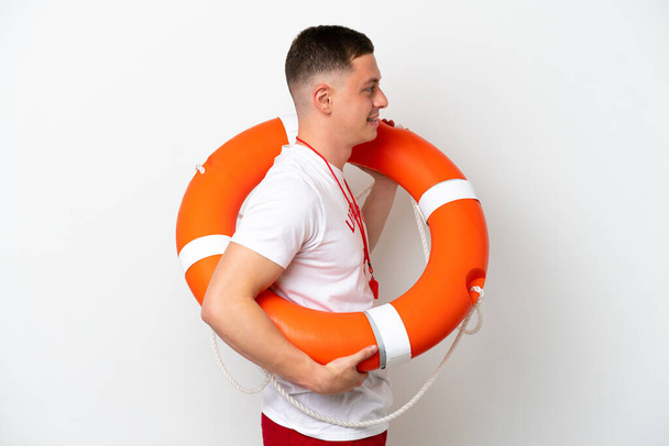 Young brazilian man isolated on white background with lifeguard equipment and with happy expression - Fotó, kép
