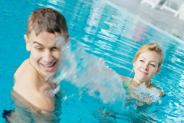 Teenage couple splashing a t the swimming pool - Foto, Bild