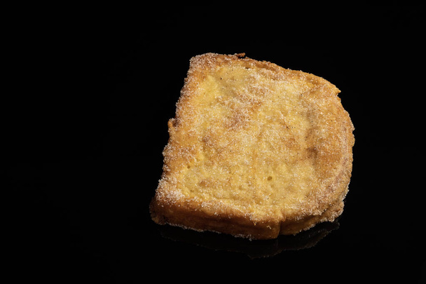 (Torrijas) Fried bread soaked in milk flavored with vanilla, cinnamon, lemon and egg on a black background. Typical Easter sweet. Concept of traditional and festive cuisine. Horizontal photo and selective focus. - Photo, Image