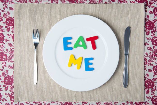 Concept: healthy food and diet - word EAT ME on a white plate - 写真・画像