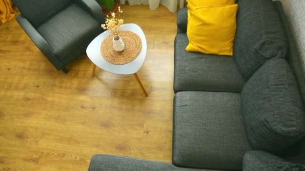 Acogedor apartamento salón con sofá y almohadas amarillas y mesa elegante, ventana con luz de día brillante al aire libre en invierno - Imágenes, Vídeo