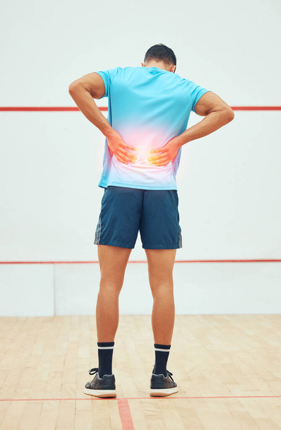 Full length rearview of unknown squash player suffering from backache during court game. Fit active mixed race athlete standing and feeling pain. Cgi and special effects on sports injury after playin. - Fotoğraf, Görsel