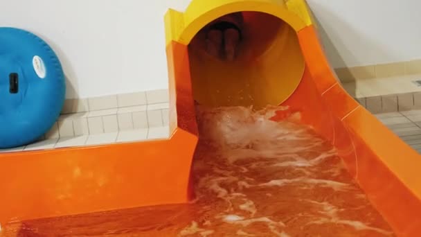 An adventurous man plunges into the pool with a splash from an orange tunnel slide. High-quality 4k footage - 映像、動画