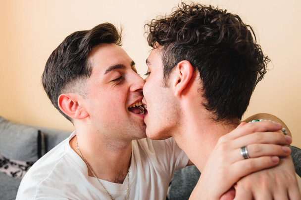 two gay men wearing white t shirts, kissing each other on the mouth. LGBT relationship. High quality photo - Foto, Imagen