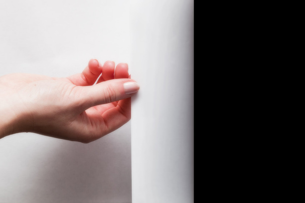 Hand pulling edge of paper - Фото, зображення