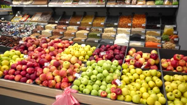Μια πολύχρωμη οθόνη με μεγάλη ποικιλία φρούτων, αποξηραμένων φρούτων, ξηρών καρπών και δημητριακών σε ένα κατάστημα βιολογικών τροφίμων. Φρούτα σε ξύλινα δοχεία σε βιτρίνα. - Πλάνα, βίντεο