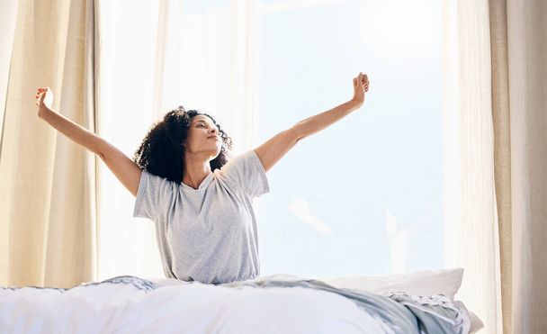 Schwarze Frau, morgens Stretching und wachen im heimischen Schlafzimmer auf, nachdem sie geschlafen oder ausgeruht hat. Entspannung, Ruhe und Komfort für junge Frauen, die sich nach dem Schlafen frisch, wach und ausgeruht im Haus fühlen - Foto, Bild
