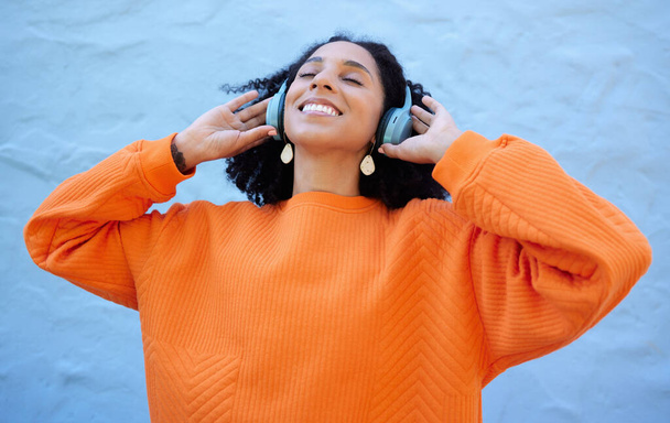 Black woman, headphones and listen to music, freedom to relax with wellness and audio streaming. Happiness, care free with radio or podcast, mindset and peace of mind with playlist on blue background. - Fotografie, Obrázek
