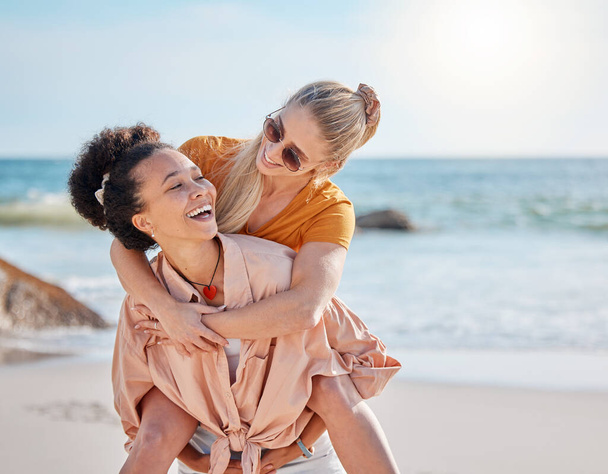 Ocean, piggyback and happy couple of friends for lgbtq, lesbian or love and freedom on summer vacation together. Blue sky, beach and diversity women on date, fun support or excited valentines holiday. - Foto, immagini