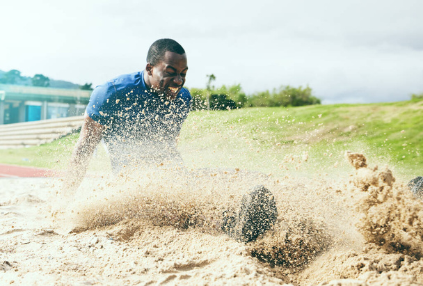 Saut en longueur, fitness et homme noir dans le sable pour le sport, l'exercice et la compétition aux États-Unis. Énergie, vitesse et entraînement des athlètes africains pour relever un défi sportif, sauter et atterrir avec puissance. - Photo, image