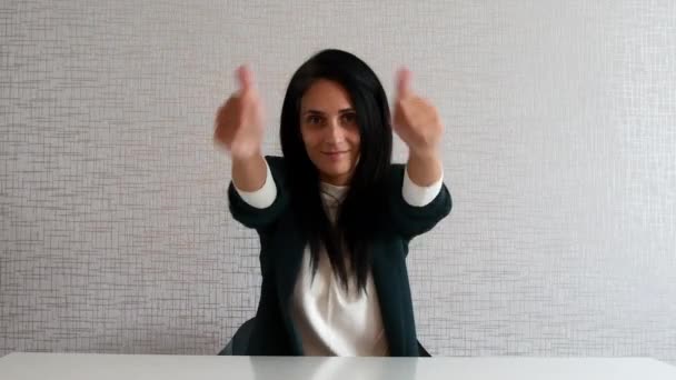 Schöne erwachsene kaukasische Frau zeigt zwei Daumen nach oben beide Hände hinter Schreibtisch, trägt formelle Büro, Universitätskleidung, empfiehlt Gesellschaft, sitzt über weißem Hintergrund - Filmmaterial, Video