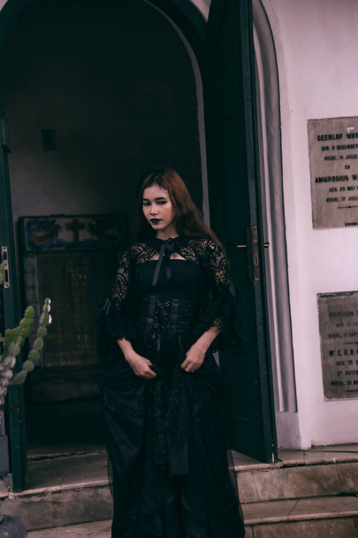 アジアの10代の若者は、夜にハロウィーンの前に魔女のような黒い化粧と黒いドレスで恐ろしい外観をしています - 写真・画像