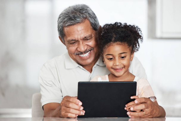 Grandfather, learning and girl with tablet in home for streaming video, movie or social media. Bonding, touchscreen and care of happy grandpa with child watching film or web browsing on technology - Photo, image