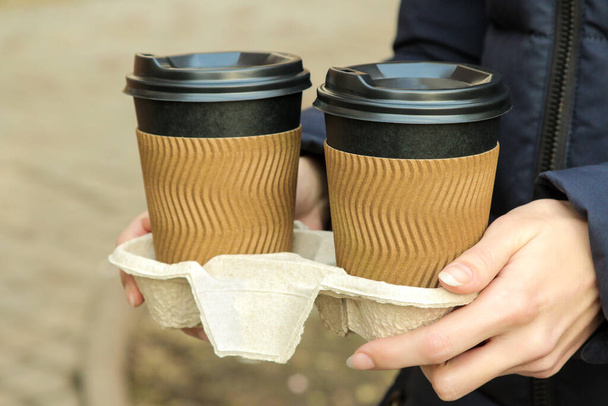 The girl holds paper cups for hot drinks in her hands. coffee to go - 写真・画像