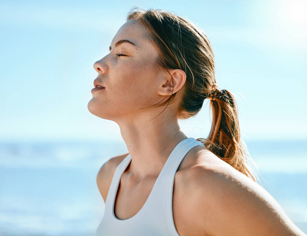 Face, breathing and sweating with an exercise woman outdoor in nature for a cardio or endurance workout. Fitness, breath or sweat and an attractive young female athlete standing with her eyes closed. - Photo, Image