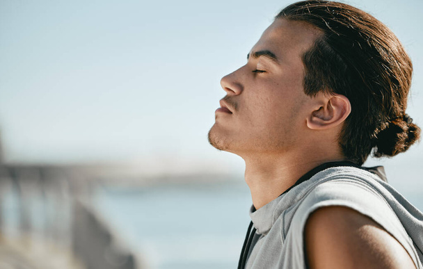 Tired, fitness and breathing man for cardio training, workout or outdoor running break on blue sky mockup. Calm, thinking and athlete or sports person with exercise in summer by beach or ocean. - Foto, Imagen