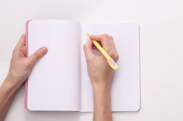 Female right hand writes in an empty notebook on a gray background - Foto, Imagen