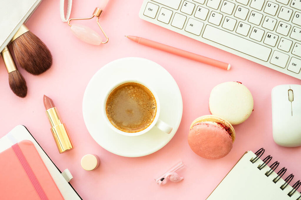 Рабочее место домашнего офиса. Креативный розовый плоский фон с клавиатурой, ноутбуком, чашкой кофе и косметикой.. - Фото, изображение