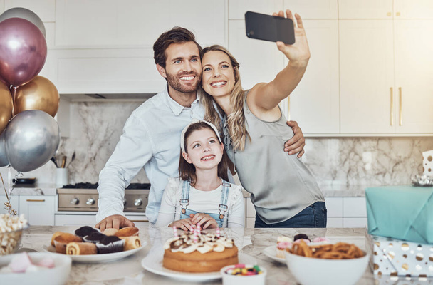 Selfie, γονείς ή κορίτσι για τον εορτασμό των γενεθλίων στο σπίτι κόμμα ή κουζίνα με ποπ κορν ή κέικ. Μητέρα, πατέρας ή παιδί που δένεται με αγάπη ή φροντίδα στο σπίτι της οικογένειας τραβήξτε φωτογραφίες για να γιορτάσετε. - Φωτογραφία, εικόνα