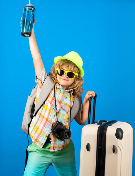 Traveler tourist kid boy 7-8 years old on isolated studio background. Travel on weekends getaway. Independent kid boy with big travel bag - 写真・画像