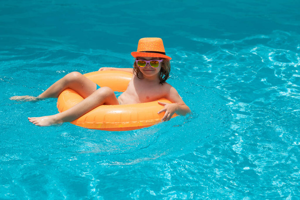 Chłopiec pluskający się w basenie. Aktywność sportów wodnych na wakacjach letnich z dziećmi - Zdjęcie, obraz